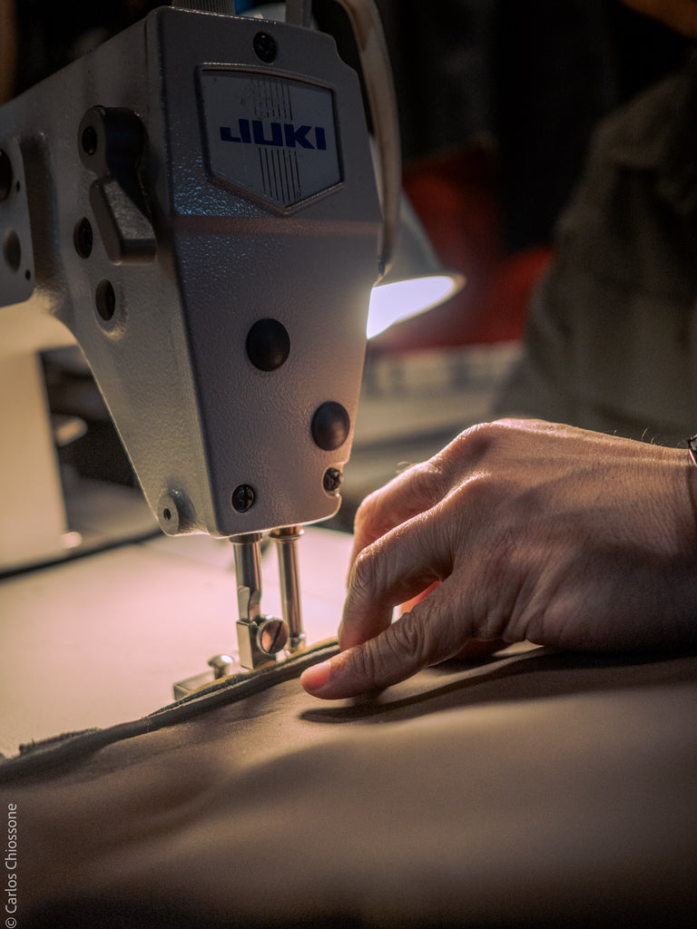 Close-up of a Juki sewing machine with a person's hand operating it.