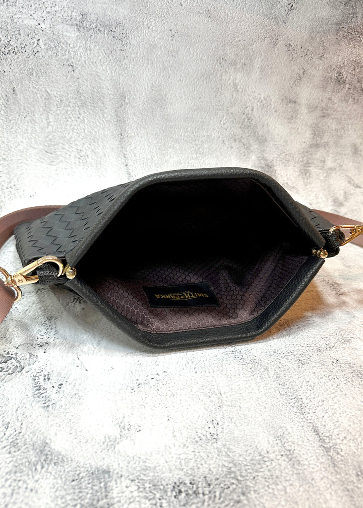 Black handbag with gold accents on a textured gray surface