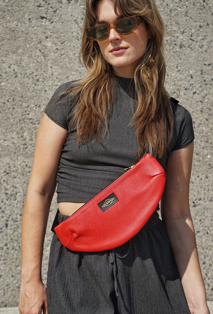 Woman wearing a red crossbody bag against a concrete wall